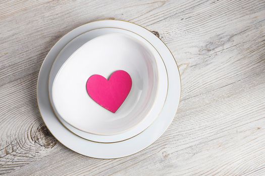 Red wooden hearts in a ceramic bowl filled with paper. Place for your text