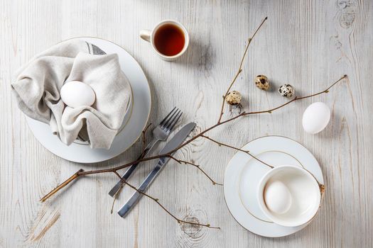 Table setting and decoration for Easter. White and partridge eggs in a plate with a napkin. poplar unblown branch