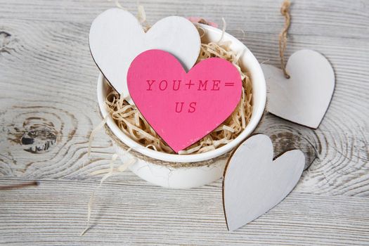 White and red wooden hearts in a ceramic bowl filled with paper. Place for your text