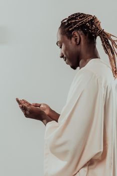 Handsome Young African Muslim Man Making Traditional Fatiha Prayer To Allah God While Wearing A Traditional Sudan fashion clothes in studio. High quality photo