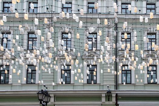 Moscow, Russia - 20 December 2021, Decorations of Stoleshnikov lane in Moscow. Large garland from electric bulbs hangs above pedestrian street. Clear blue sky in the background. Travel in Russia theme.