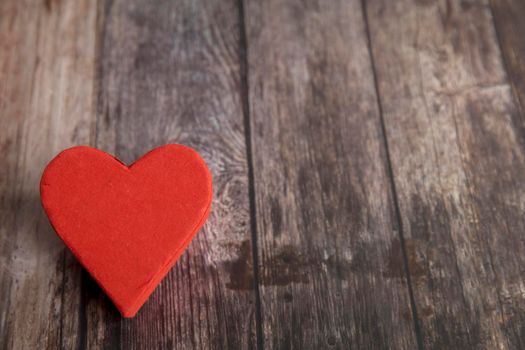 The red paper heart is on a wooden brown table. The day of Valentine. Copy space