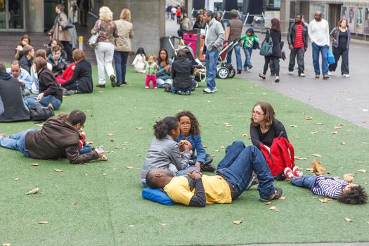 London, UK - 20 July 2019, Families with children relax on an artificial grass lawn in the city center.