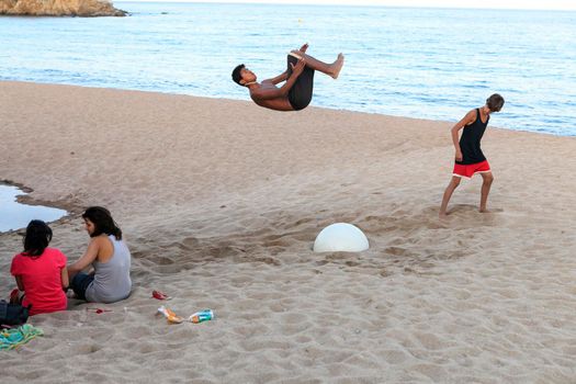 Barcelona, Spain -20 July 2020, A young man is engaged in acrobatics on the beach. Somersault jump