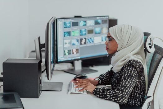 Young Afro-American modern Muslim businesswoman wearing a scarf in a creative bright office workplace with a big screen. High-quality photo