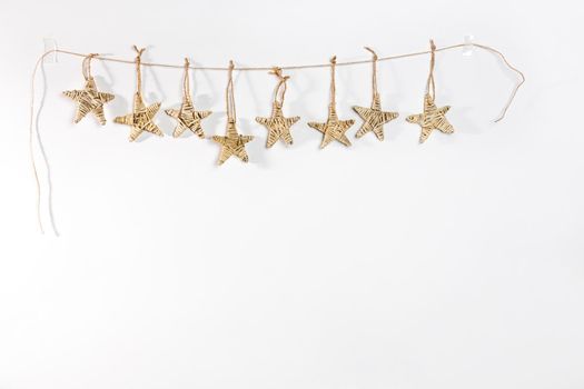 A handmade garland of braided stars is on a white wall. Place for text. Copy space