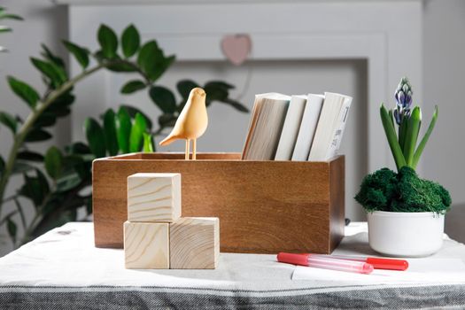 Wooden container with books, three cubes on the table against the background of a white fireplace. Place for text. Valentine's Day