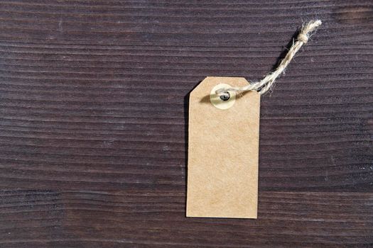 Blank white tag with string on wooden brown background. Copy space