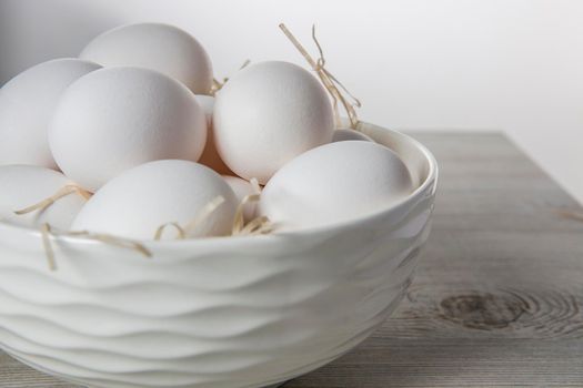 Patterned bowl with eggs on beige wooden table in white scandinavian style kitchen. Place for text. Copy space