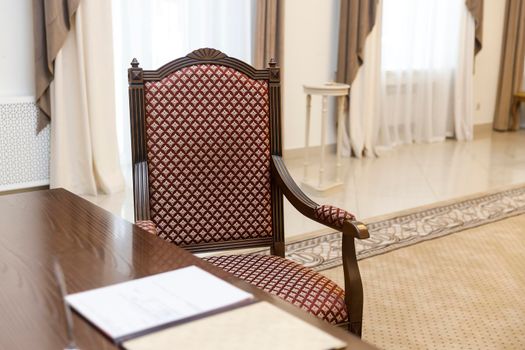 Standard wedding registration hall in Moscow. A red armchair in the Empire style at the wooden table, where the spouses sign the act of registering the wedding.