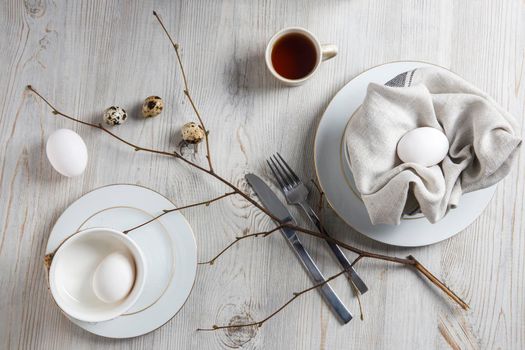 Table setting and decoration for Easter. White and partridge eggs in a plate with a napkin. poplar unblown branch