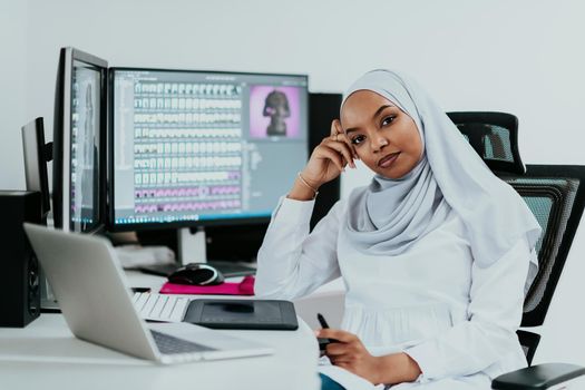 Young Afro-American modern Muslim businesswoman wearing a scarf in a creative bright office workplace with a big screen. High-quality photo