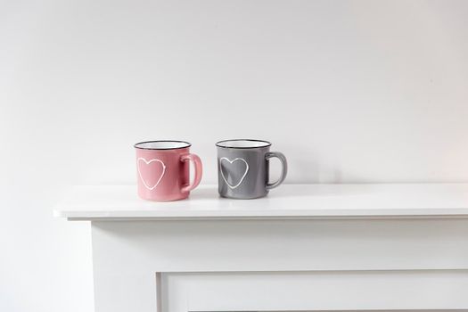 A pink and gray mug with a painted white heart are located on the fireplace. Scandinavian style. Copy space