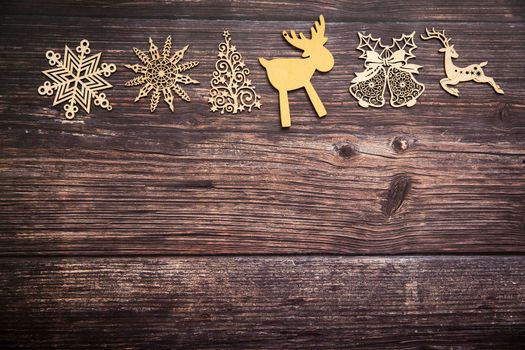 Wooden handmade snowflake toys on dark wooden Christmas background. Crafts cut from eco friendly wood material. Ecological home decor for winter holiday. Copy space. Frame