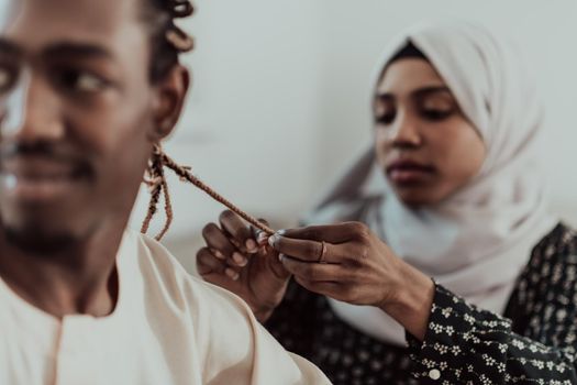 A young Muslim couple has a romantic time at home while the woman makes the hairstyle for her husband female wearing traditional Sudan Islamic hijab clothes. High-quality photo