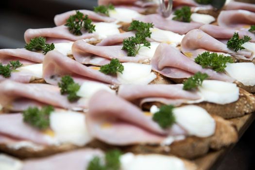 Ham and parsley sandwiches arranged in a row at a buffet table