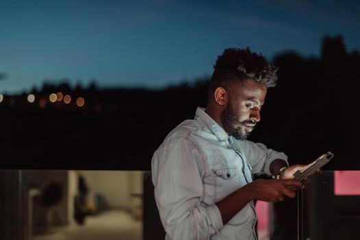 The young man on an urban city street at night texting on a smartphone with bokeh and neon city lights in the background. High-quality photo. High-quality photo