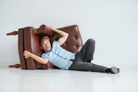 Brutal man in a shirt with short sleeves sitting in the chair, his fists clenched, slightly bent, under the gaze of the forehead. High quality photo