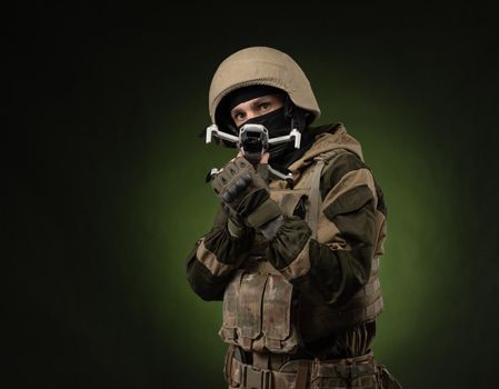 soldier in military clothes with a weapon launches a small unmanned quadcopter for reconnaissance on a dark background