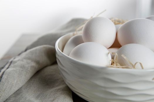 Patterned bowl with eggs on beige wooden table in white scandinavian style kitchen. Place for text. Copy space