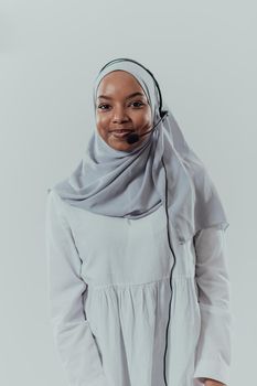 African Muslim female with hijab scarf customer representative businesswoman with phone headset helping and supporting online with the customer in modern bright call center isolated on white background. High-quality photo