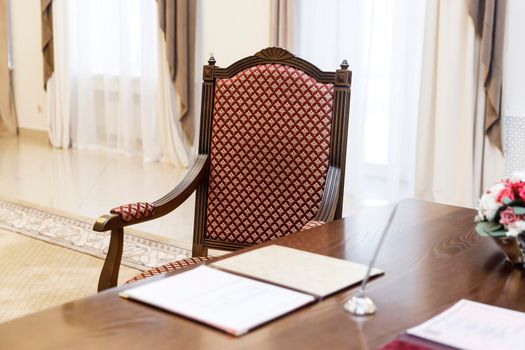 Standard wedding registration hall in Moscow. A red armchair in the Empire style at the wooden table, where the spouses sign the act of registering the wedding.