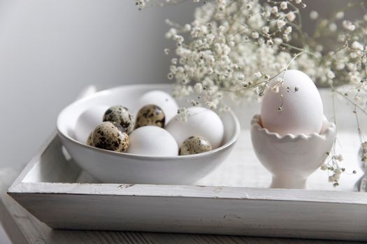 Table decorated for Easter in beige tones. Dried gypsophila, chicken and quail eggs and a cup of coffee. Easter concept.