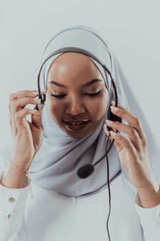 African Muslim female with hijab scarf customer representative businesswoman with phone headset helping and supporting online with the customer in modern bright call center isolated on white background. High-quality photo