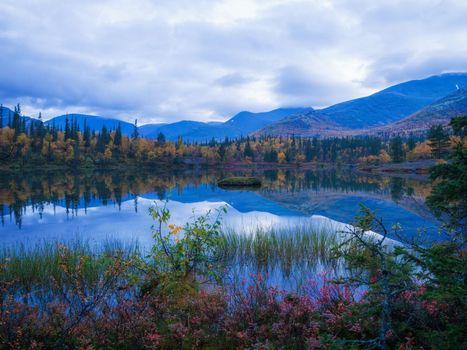 Reflection of mountains and clouds in the calm surface of the lake. Peaceful landscape. Khibiny. photo