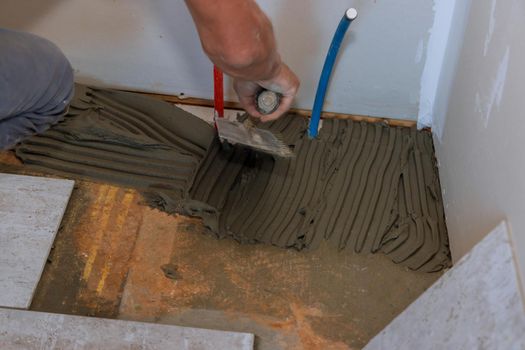 Worker applying tile adhesive on the floor for ceramic tile