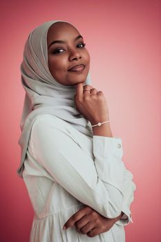 Portrait of young modern Muslim afro beauty wearing traditional Islamic clothes on plastic pink background. Selective focus. High-quality photo