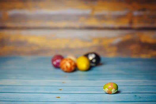 Easter colored painted small egg on blue and brown blurry wooden background with copyspace