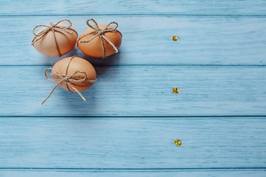 Easter beige eggs decorate with rope on blue wooden background with copyspace