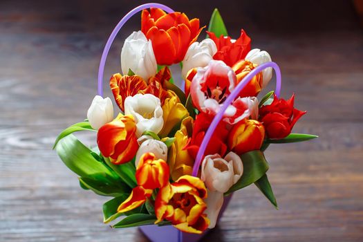 bouquet of different color tulips on a dark wooden background at springtime