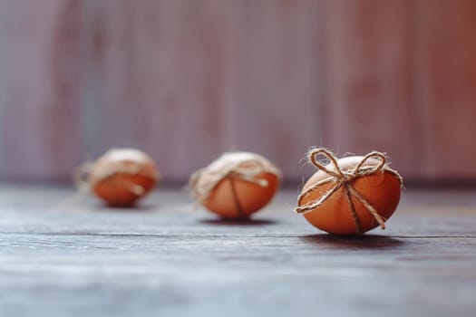 Easter beige eggs decorate with rope on brown wooden background with copyspace