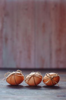 Easter beige eggs decorate with rope on brown wooden background with copyspace