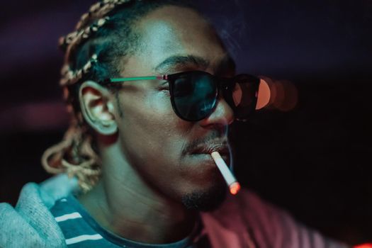 Afro Americans smoking a cigar, in the background city lights. High quality photo