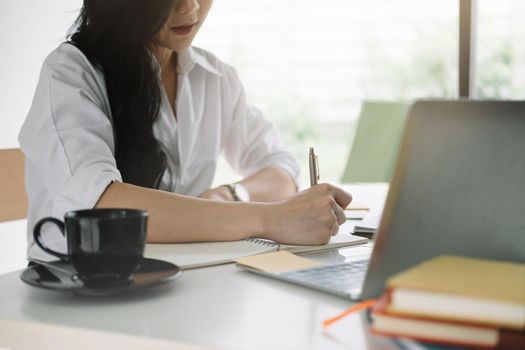 attractive woman writing in notepad while watching webinar on laptop.