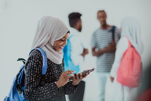 African female student with a group of friends in the background wearing traditional Islamic hijab clothes. Selective focus. High-quality photo