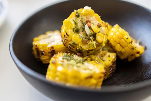 Chopped, grilled spiced corn in a black ceramic plate