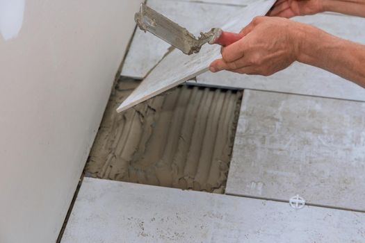 Man installs placing the ceramic tile over floor with home construction working