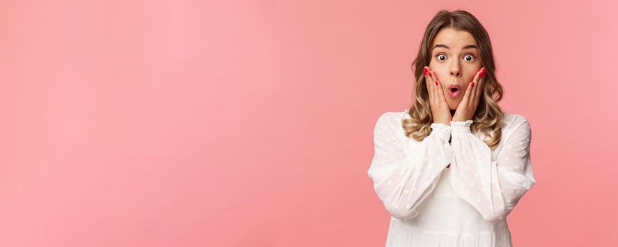 No way, what a story. Stunned and amazed blond girl listening to gossips with excitement and interest, hold hands on cheeks say wow and stare astonished camera, standing pink background.