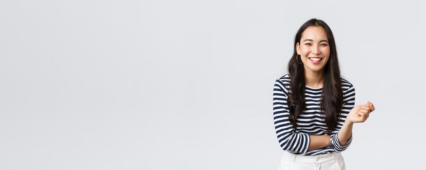 Lifestyle, people emotions and casual concept. Carefree happy outgoing asian woman having fun talking to people, laughing and smiling upbeat, standing white background cheerful.