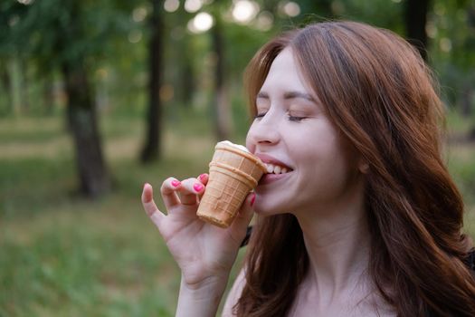 Smiling cheerful ukrainian brunette young woman eating ice cream outdoors.