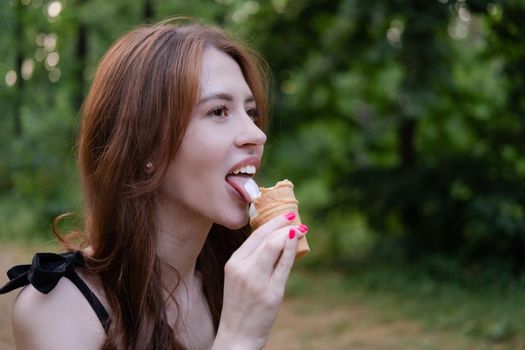 Smiling cheerful ukrainian brunette young woman eating ice cream outdoors.