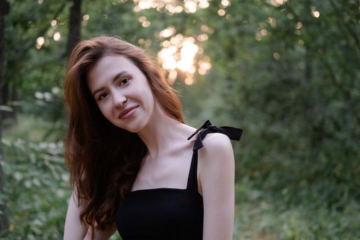 attractive young brunette woman in a black dress posing in the forest. freedom. fashion portrait.