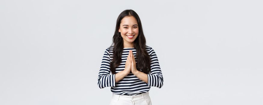 Lifestyle, people emotions and casual concept. Cute asian girl in casual outfit smiling as saying namaste, holding hands in pray, pleading or greeting guests with polite bow.