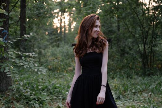 attractive young brunette woman in a black dress posing in the forest. freedom. fashion portrait.