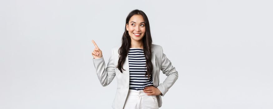 Business, finance and employment, female successful entrepreneurs concept. Cheerful successful businesswoman in white suit pointing fingers upper left corner, showing advertisement.