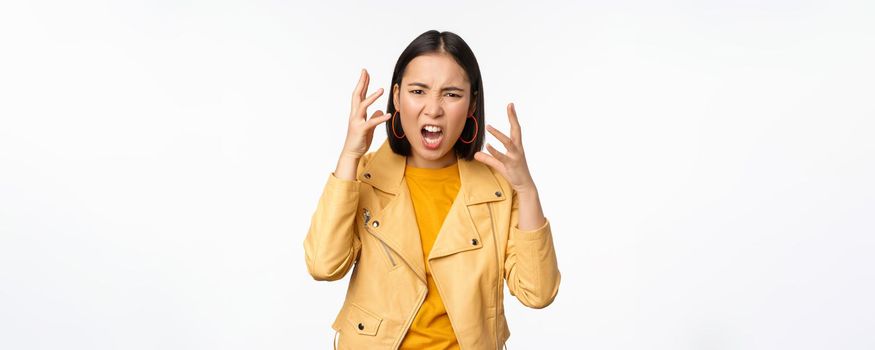 Asian angry woman arguing, shaking hands angry and screaming, shouting with frustrated face, standing over white background.